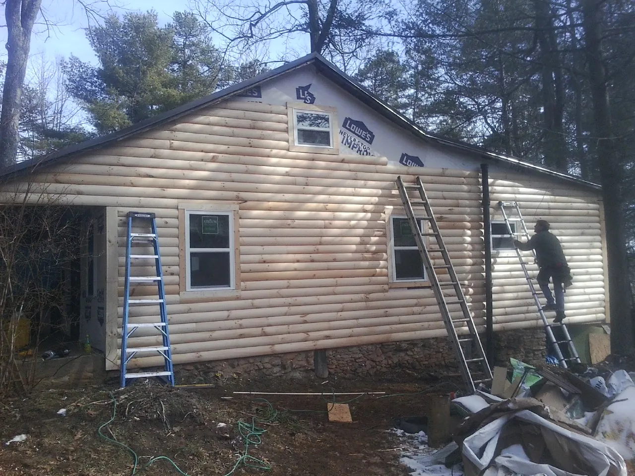 Ladders set against fresh log siding during an exterior remodel in Kiowa