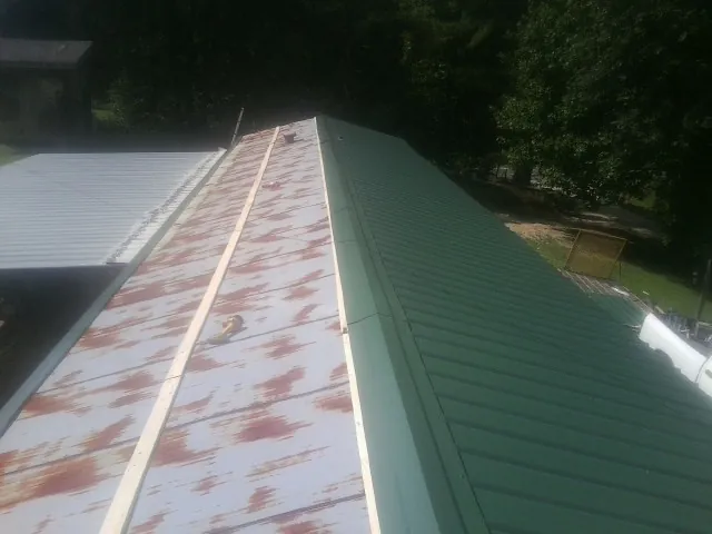 Old rusted panels beside newly installed green metal roofing — Wind Damage Roof Repair by Roofing Brothers in Kiowa