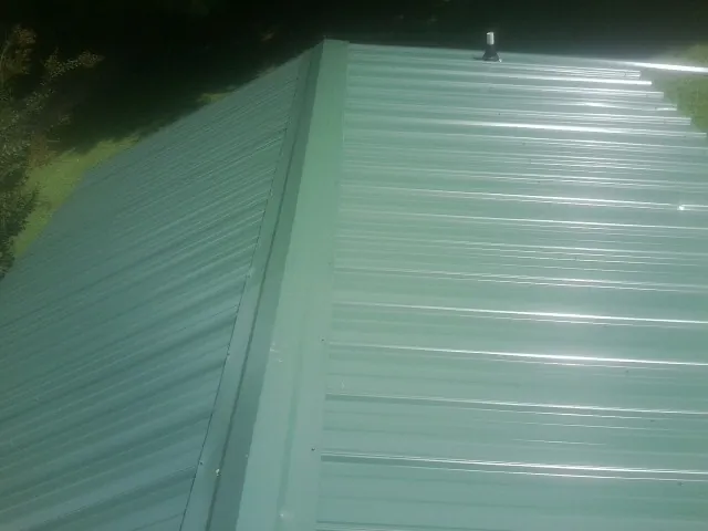 New green metal panels meeting at the ridge of a roof — Flat Roof Repair work by our crew in Kiowa