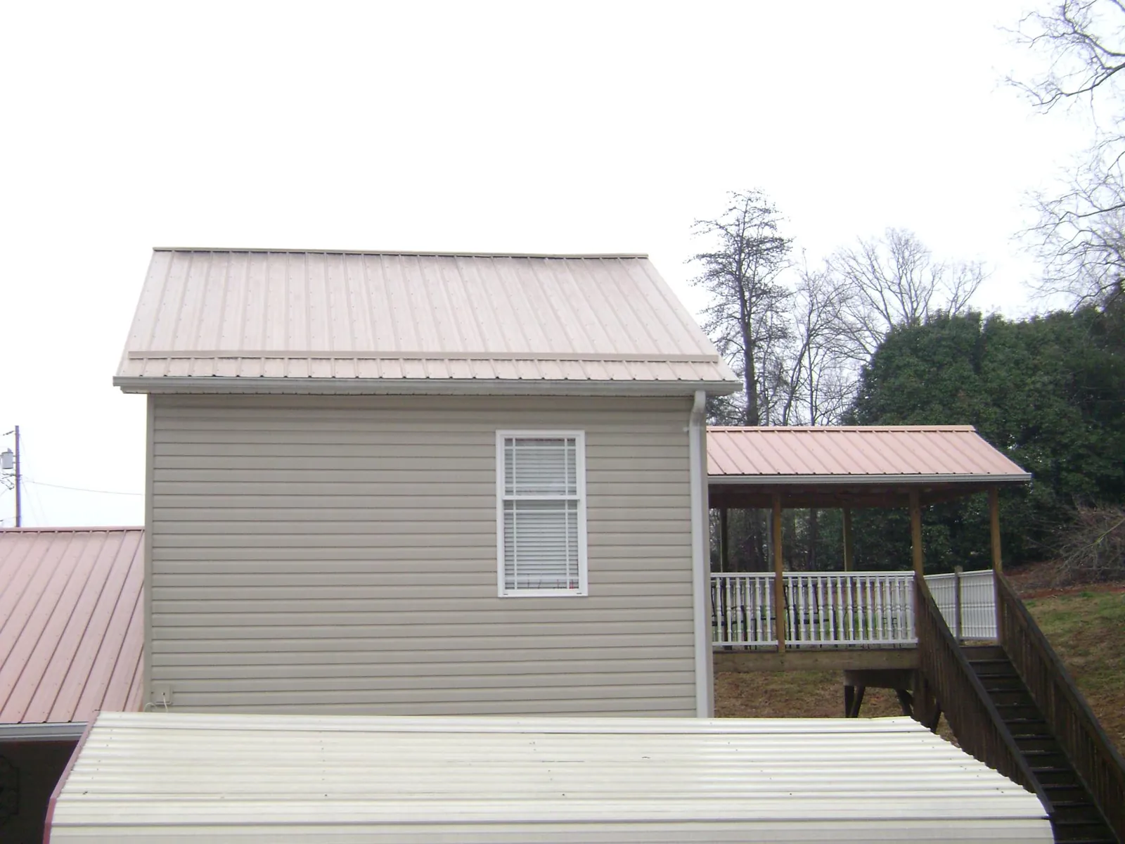 Tan metal roofs on a two story addition and attached porch, from a Roof Replacement job in Kiowa